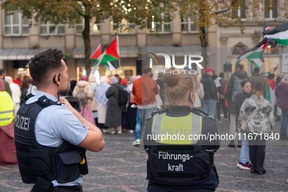 Police observe the demonstration site as dozens of pro-Palestinian activists gather at Muenster Square and protest against deadly Israeli ai...