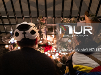 This photograph shows bunches of mainly white flowers displayed with candles as cyclists pay tribute to Paul, 27, a cyclist who was run over...