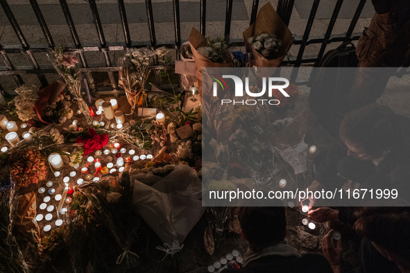 This photograph shows bunches of mainly white flowers displayed with candles as cyclists pay tribute to Paul, 27, a cyclist who was run over...