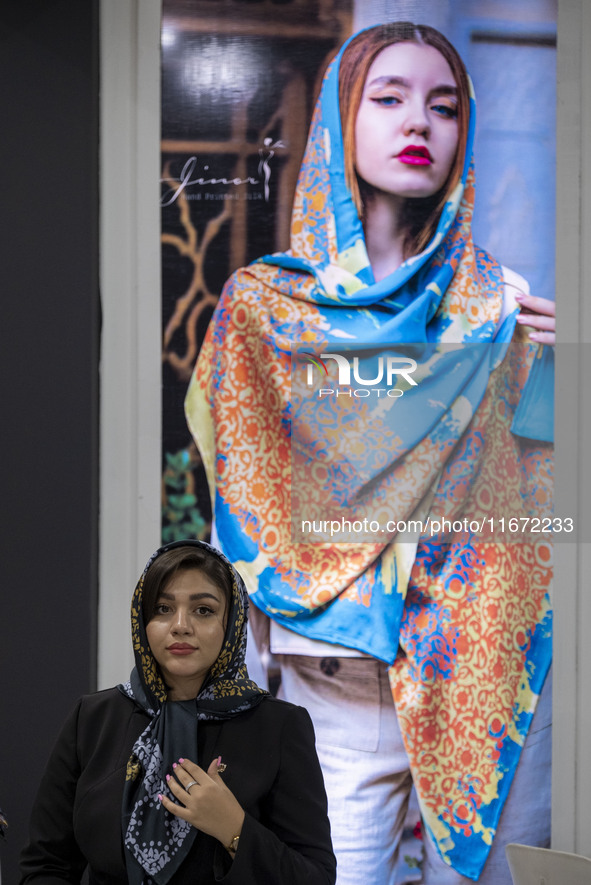 A young Iranian woman stands beneath a portrait of a female model during the 11th National Handicrafts and 3rd International Tourism Exhibit...