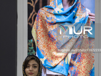 A young Iranian woman stands beneath a portrait of a female model during the 11th National Handicrafts and 3rd International Tourism Exhibit...