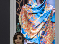 A young Iranian woman stands beneath a portrait of a female model during the 11th National Handicrafts and 3rd International Tourism Exhibit...