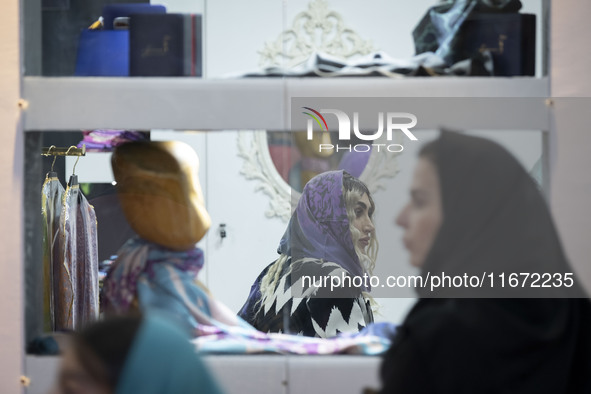 An Iranian female fashion designer sits at a stand during the 11th National Handicrafts and 3rd International Tourism Exhibition in the hist...