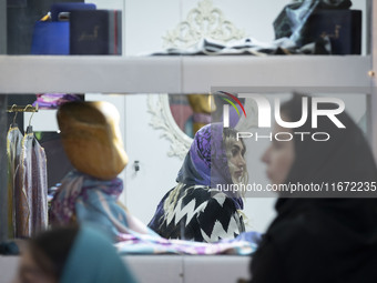 An Iranian female fashion designer sits at a stand during the 11th National Handicrafts and 3rd International Tourism Exhibition in the hist...