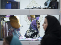 An Iranian female fashion designer sits at a stand during the 11th National Handicrafts and 3rd International Tourism Exhibition in the hist...