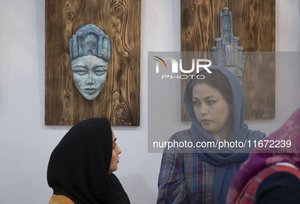 Two Iranian female artists sit at their stand during the 11th National Handicrafts and 3rd International Tourism Exhibition in the historica...