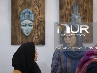 Two Iranian female artists sit at their stand during the 11th National Handicrafts and 3rd International Tourism Exhibition in the historica...