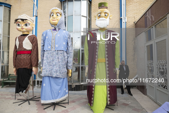 An Iranian man speaks on his cellphone while standing next to effigies during the 11th National Handicrafts and 3rd International Tourism Ex...