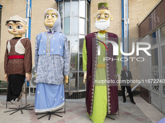 An Iranian man speaks on his cellphone while standing next to effigies during the 11th National Handicrafts and 3rd International Tourism Ex...