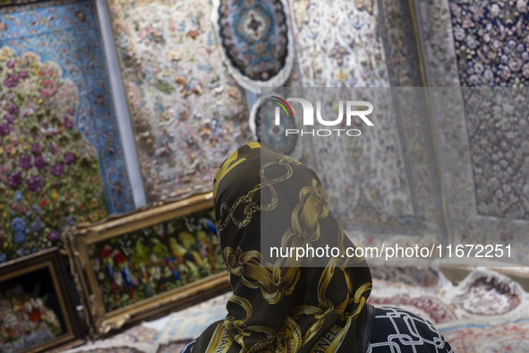 A woman looks at Iranian handwoven rugs while visiting the 11th National Handicrafts and 3rd International Tourism Exhibition in the histori...