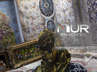 A woman looks at Iranian handwoven rugs while visiting the 11th National Handicrafts and 3rd International Tourism Exhibition in the histori...