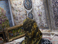 A woman looks at Iranian handwoven rugs while visiting the 11th National Handicrafts and 3rd International Tourism Exhibition in the histori...