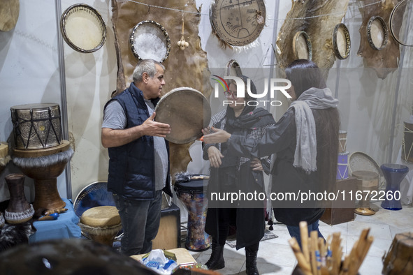 An Iranian trader plays a traditional musical instrument for women visiting the 11th National Handicrafts and 3rd International Tourism Exhi...