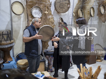 An Iranian trader plays a traditional musical instrument for women visiting the 11th National Handicrafts and 3rd International Tourism Exhi...