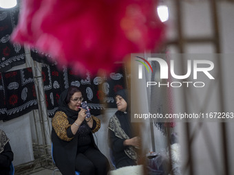 An Iranian female trader applies makeup while sitting at her stand during the 11th National Handicrafts and 3rd International Tourism Exhibi...