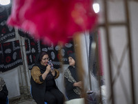 An Iranian female trader applies makeup while sitting at her stand during the 11th National Handicrafts and 3rd International Tourism Exhibi...