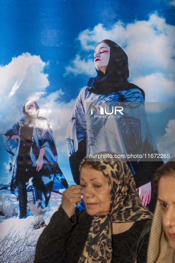 Two Iranian women walk past portraits of female models during the 11th National Handicrafts and 3rd International Tourism Exhibition in Tabr...