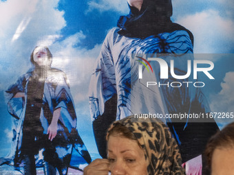 Two Iranian women walk past portraits of female models during the 11th National Handicrafts and 3rd International Tourism Exhibition in Tabr...