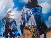 Two Iranian women walk past portraits of female models during the 11th National Handicrafts and 3rd International Tourism Exhibition in Tabr...