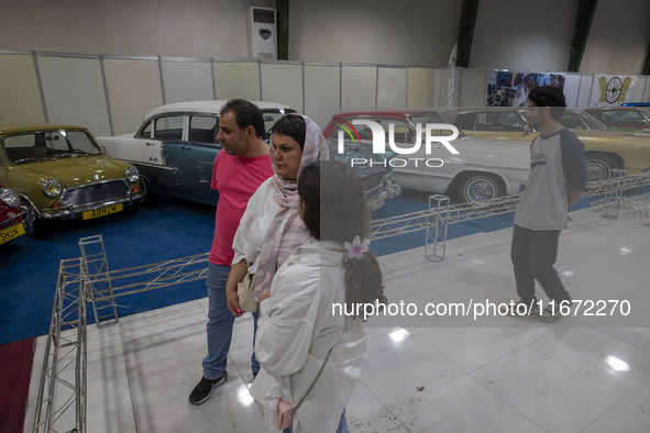 An Iranian family looks at classic cars while visiting the 11th National Handicrafts and 3rd International Tourism Exhibition in the histori...