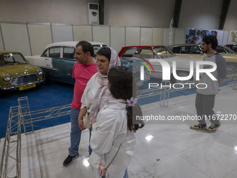 An Iranian family looks at classic cars while visiting the 11th National Handicrafts and 3rd International Tourism Exhibition in the histori...