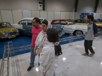 An Iranian family looks at classic cars while visiting the 11th National Handicrafts and 3rd International Tourism Exhibition in the histori...