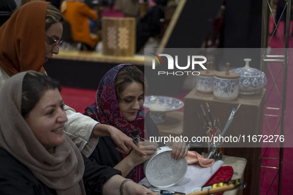 An Iranian female artist works at a stand during the 11th National Handicrafts and 3rd International Tourism Exhibition in the historical ci...