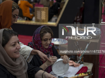 An Iranian female artist works at a stand during the 11th National Handicrafts and 3rd International Tourism Exhibition in the historical ci...