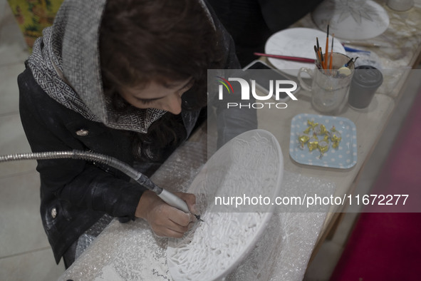 An Iranian female artist works at a stand during the 11th National Handicrafts and 3rd International Tourism Exhibition in the historical ci...