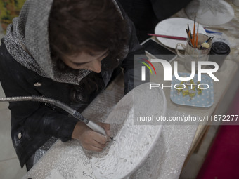 An Iranian female artist works at a stand during the 11th National Handicrafts and 3rd International Tourism Exhibition in the historical ci...