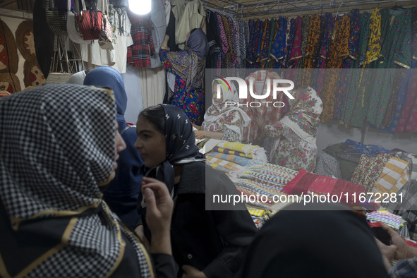 An Iranian saleswoman adjusts dresses while women shop during the 11th National Handicrafts and 3rd International Tourism Exhibition in the...