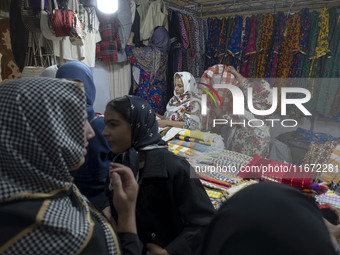 An Iranian saleswoman adjusts dresses while women shop during the 11th National Handicrafts and 3rd International Tourism Exhibition in the...