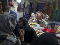 An Iranian saleswoman adjusts dresses while women shop during the 11th National Handicrafts and 3rd International Tourism Exhibition in the...