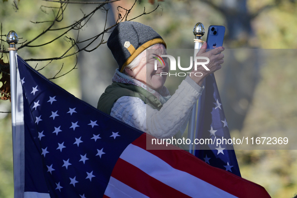 A supporter stands between American flags as U.S. Vice President Kamala Harris greets supporters after a campaign event with a group of curr...