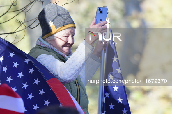 A supporter stands between American flags as U.S. Vice President Kamala Harris greets supporters after a campaign event with a group of curr...