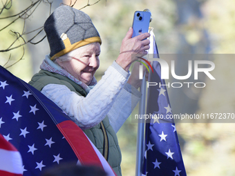 A supporter stands between American flags as U.S. Vice President Kamala Harris greets supporters after a campaign event with a group of curr...