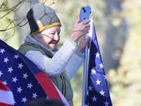 A supporter stands between American flags as U.S. Vice President Kamala Harris greets supporters after a campaign event with a group of curr...