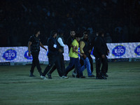 A cricket fan is tackled by security personnel following a pitch invasion during the finals of the Legends League Cricket T20 match between...