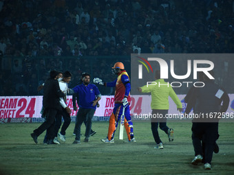 Cricket fans are tackled by security men following a pitch invasion during the finals of the Legends League Cricket T20 match between Southe...