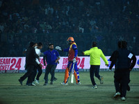 Cricket fans are tackled by security men following a pitch invasion during the finals of the Legends League Cricket T20 match between Southe...