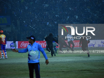 Cricket fans are tackled by security men following a pitch invasion during the finals of the Legends League Cricket T20 match between Southe...