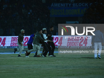 A cricket fan is led away following a pitch invasion during the finals of the Legends League Cricket T20 match between Southern Superstars a...