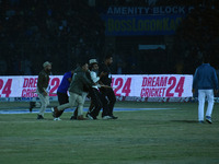 A cricket fan is led away following a pitch invasion during the finals of the Legends League Cricket T20 match between Southern Superstars a...