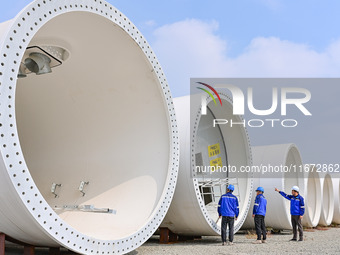 Technicians check the quality of a wind power tower barrel at a wind power equipment manufacturing enterprise in Weinan, China, on October 1...