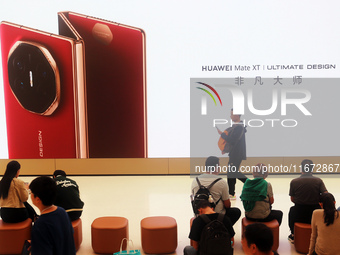 A customer experiences the Mate XT, a triple foldable screen phone, at Huawei's global flagship store in Shanghai, China, on October 15, 202...