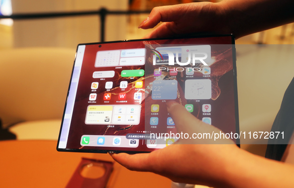 A customer experiences the Mate XT, a triple foldable screen phone, at Huawei's global flagship store in Shanghai, China, on October 15, 202...