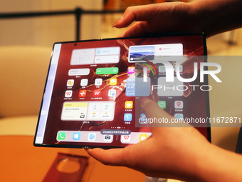 A customer experiences the Mate XT, a triple foldable screen phone, at Huawei's global flagship store in Shanghai, China, on October 15, 202...