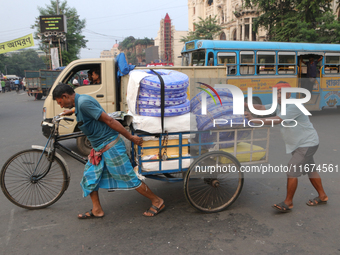 Indian laborers push a cycle van loaded with goods across a busy road in Kolkata, India, on October 17, 2024. (