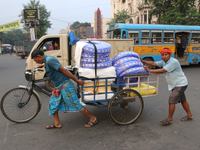 Indian laborers push a cycle van loaded with goods across a busy road in Kolkata, India, on October 17, 2024. (