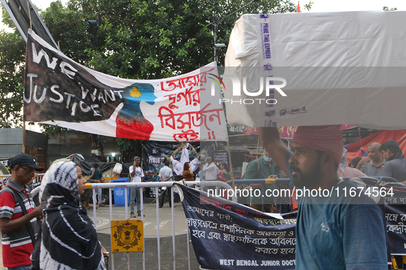 Indian daily laborers carry goods and walk past a doctor protest site in Kolkata, India, on October 17, 2024. 